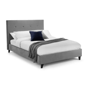 Gray upholstered bed with white bedding and a dark blue pillow on a white background