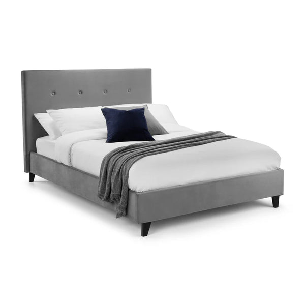 Gray upholstered bed with white bedding and a dark blue pillow on a white background