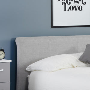 Gray upholstered bed with white bedding against a blue wall with a framed picture.
