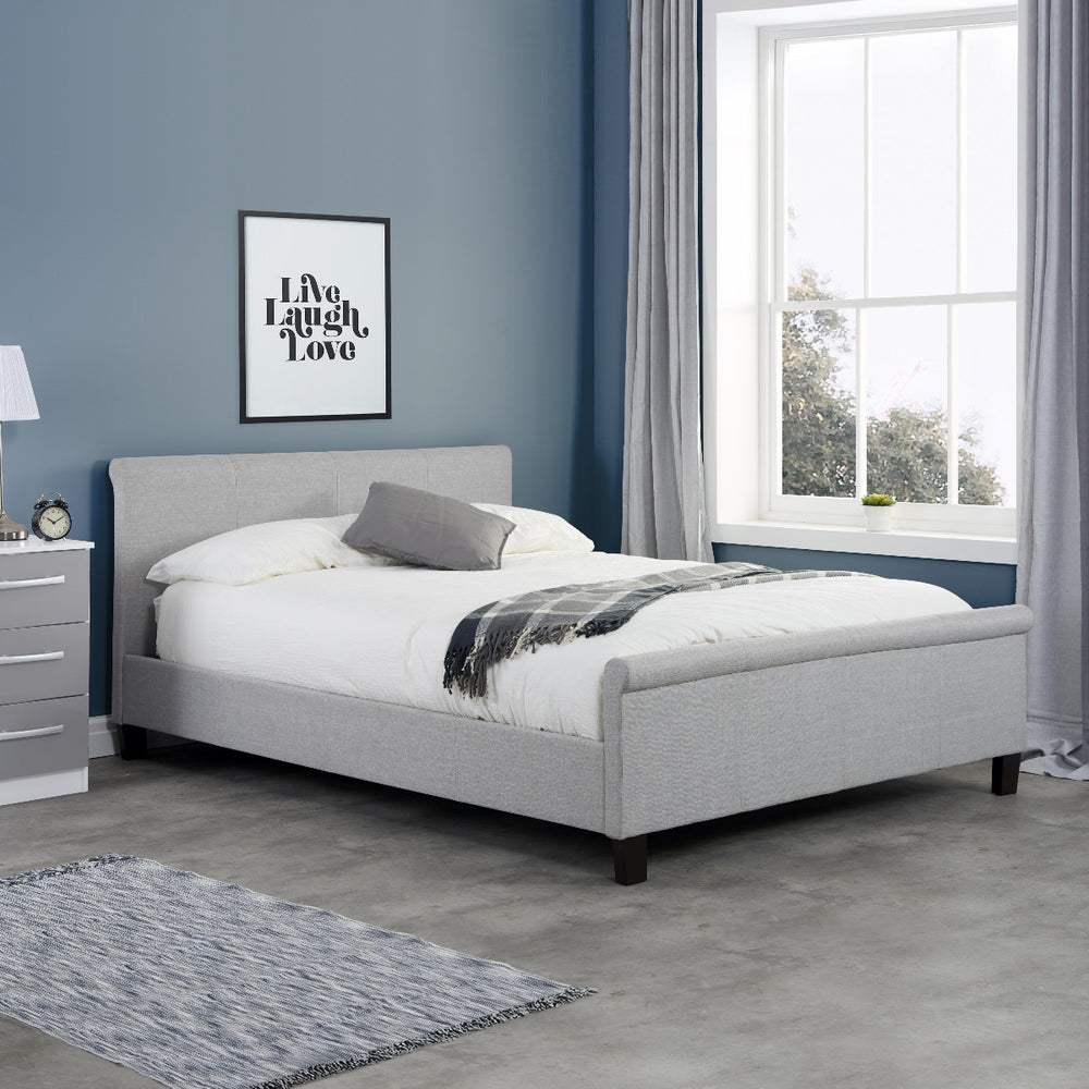 Gray upholstered bed with white mattress on a white background