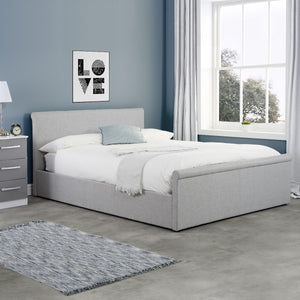 Gray upholstered bed in a bedroom with a window and decorative elements.