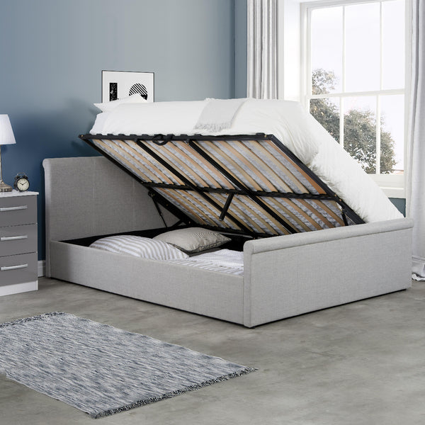 Gray upholstered bed with raised base in a bedroom setting.