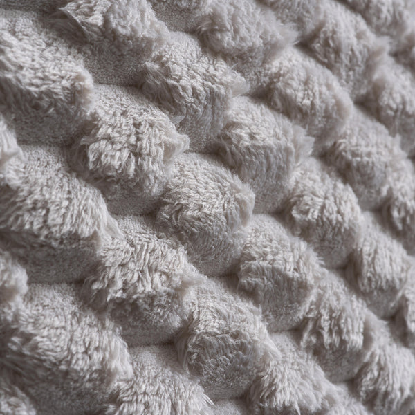 Close-up of textured beige fabric with a knitted pattern