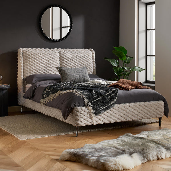 Modern bedroom with a textured bed and decorative pillows.