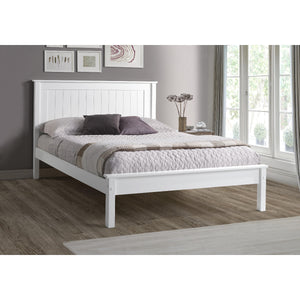 White wooden bed in a bedroom with a gray wall and window.