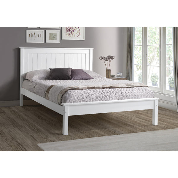 White wooden bed in a bedroom with a gray wall and window.