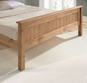 Wooden bed frame with beige bedding on a light wooden floor.