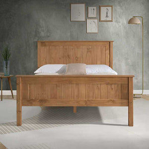 Wooden bed with white bedding against a gray wall with framed pictures.