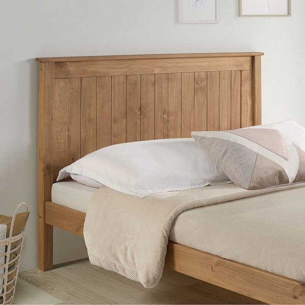 Wooden bed with beige bedding and white pillows in a bedroom setting.