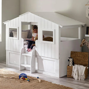 Children's room with a white playhouse bed and toys on the floor.