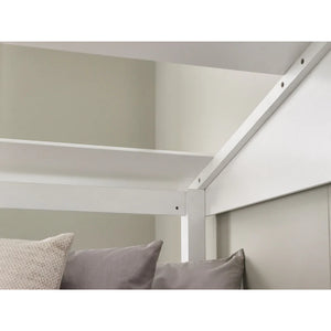 White bed frame with pillows against a neutral wall