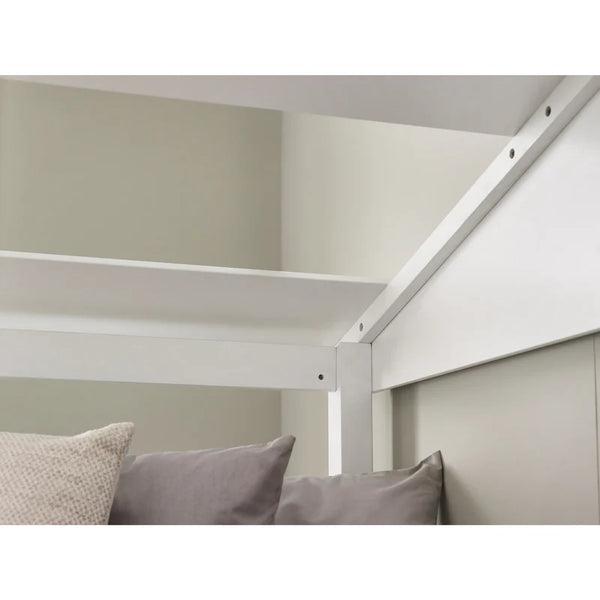 White bed frame with pillows against a neutral wall