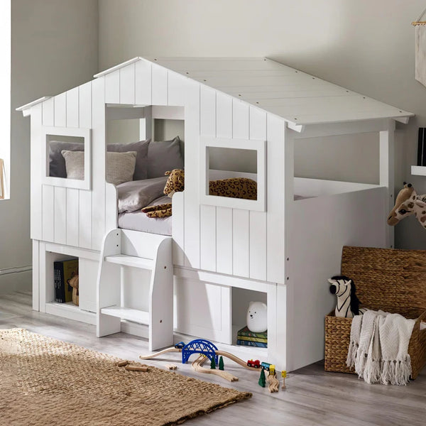 White children's playhouse bed with toys and a rug on the floor
