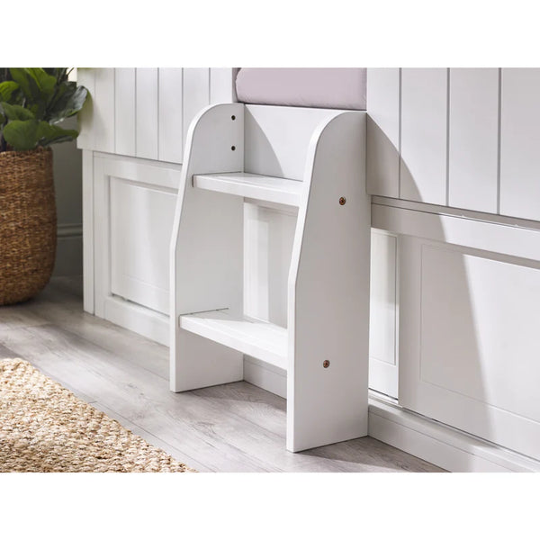 White step stool in a room with wooden flooring and a plant.