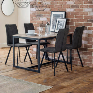 Dining area with a table and four chairs against a brick wall.