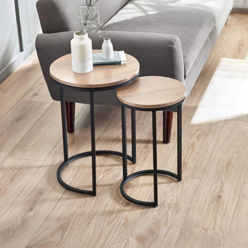 Set of two round side tables with wooden tops and black metal frames on a white background