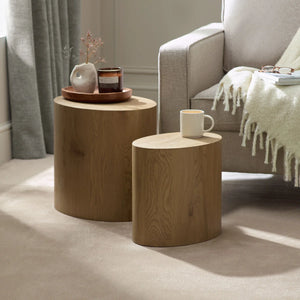 Two wooden side tables with a mug and decorative items in a living room setting.