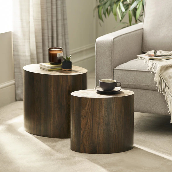 Two wooden side tables with a cup and candle in a living room setting.