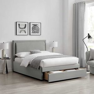 Gray upholstered bed with storage drawers in a bedroom setting.