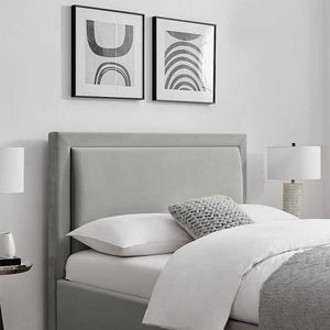Gray upholstered bed with white bedding and abstract art on a white wall