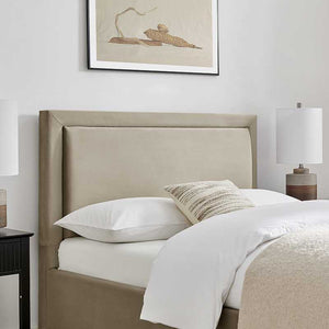 Beige upholstered headboard with white bedding and a lamp on a nightstand in a bedroom setting.