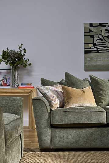 Pillow back sofa in green colour with grey walls in background