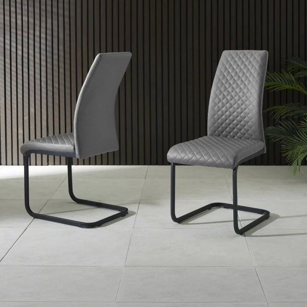 Two gray chairs with quilted design on a tiled floor.