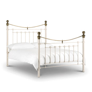 White metal bed with brass accents on a white background