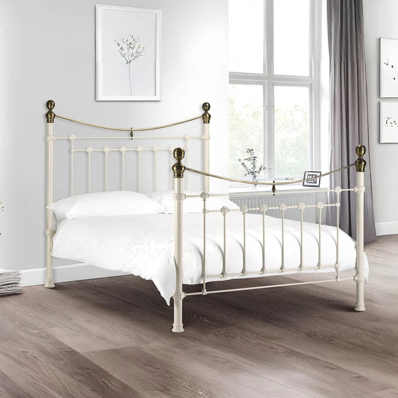 White metal bed with brass accents on a white background