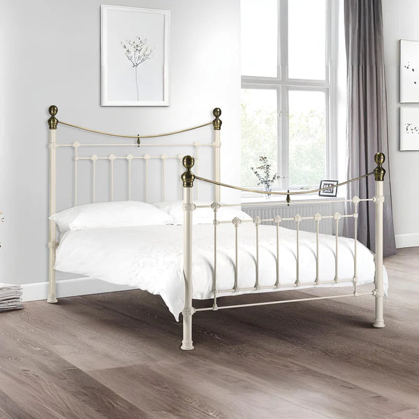 White metal bed with brass accents in a bedroom setting