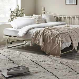 Bedroom with a bed, pillows, and a blanket on a wooden floor.