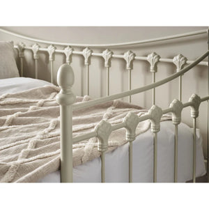 Close-up of a decorative metal bed frame with a textured blanket on a white background
