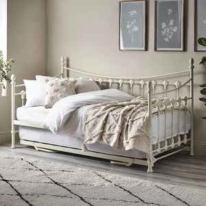 Vintage-style metal bed with white bedding in a bedroom setting.