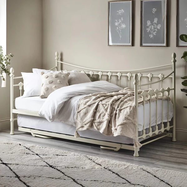 Vintage-style metal bed with white bedding in a bedroom setting.