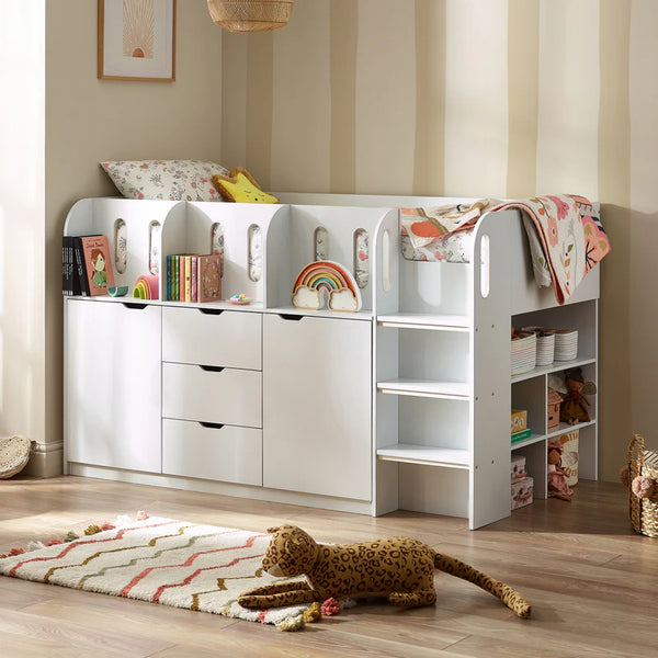 Children's room with a white storage unit, books, and toys on a wooden floor.