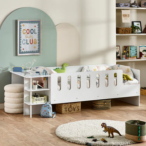 Children's room with a white crib, shelves, and toys on a wooden floor.