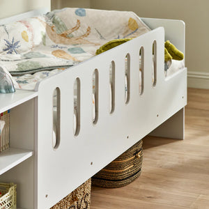 White children's bed with a wooden floor and neutral wall background