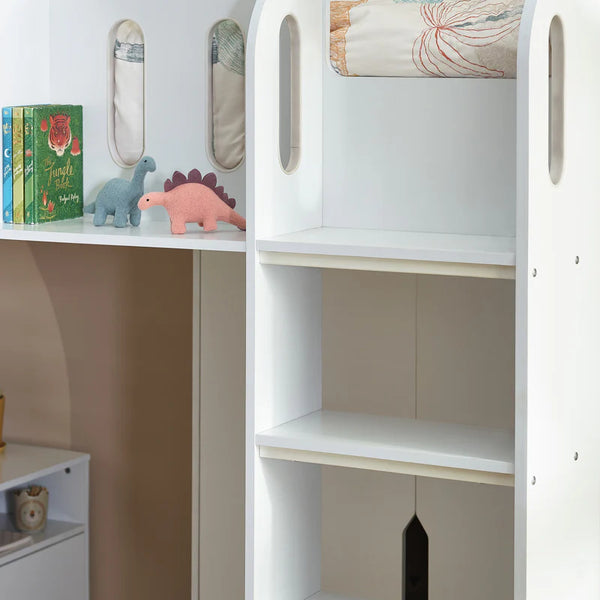 White children's bookshelf with books, toys, and decorative items against a beige wall.