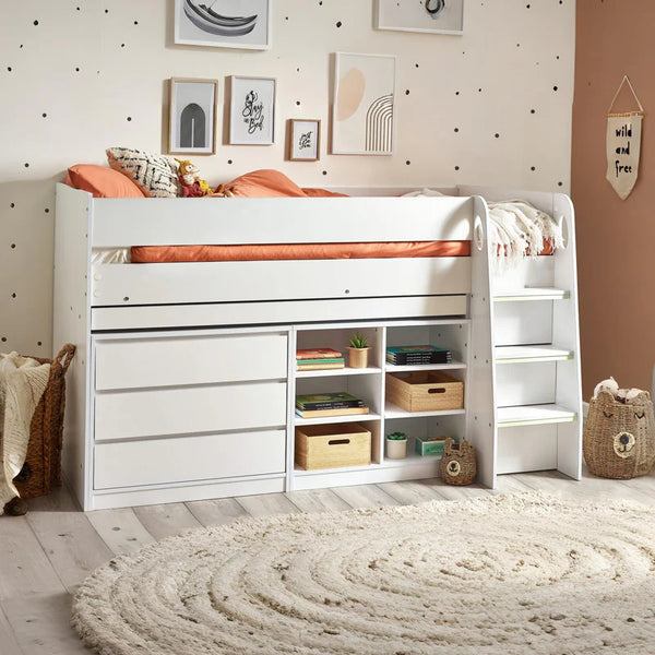 White children's bed with storage drawers and shelves in a room with polka dot wallpaper.