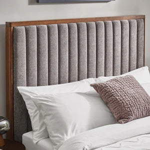 Gray upholstered headboard with wooden frame and pillows on a bed