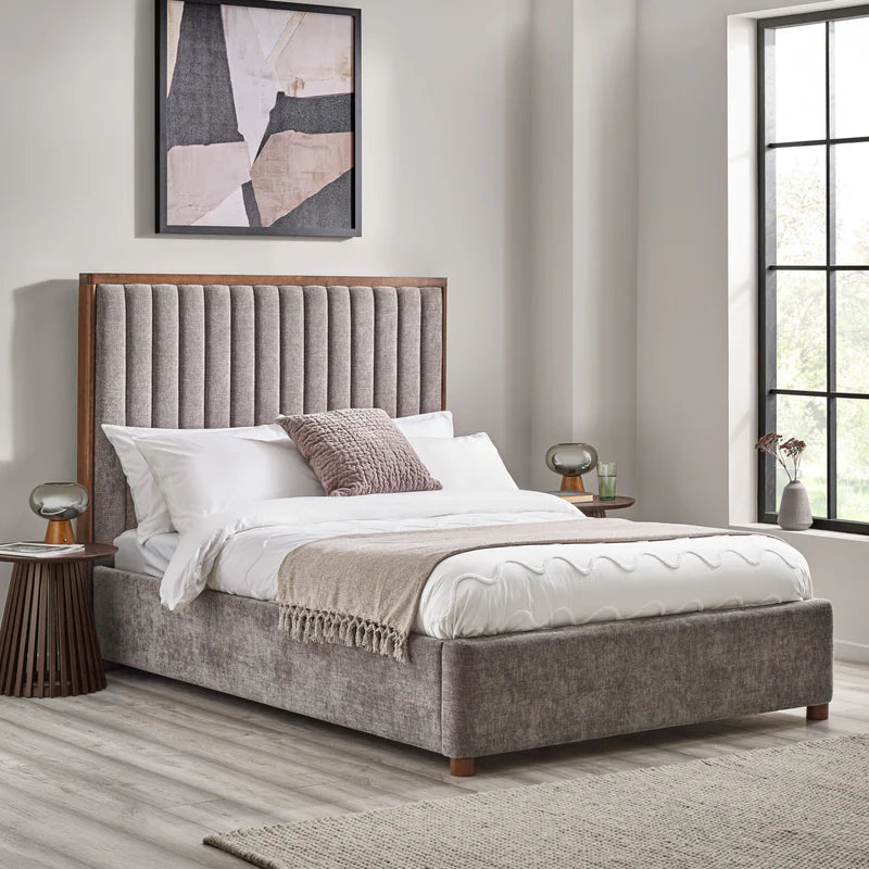 Gray upholstered bed with white bedding on a white background