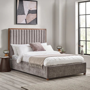 Gray upholstered bed with wooden headboard in a bedroom setting.