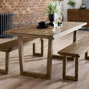 Wooden dining table with benches in a room with brick wall and radiator.