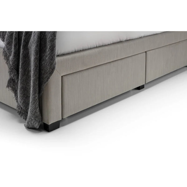 Gray upholstered bed with a dark gray blanket on a white background