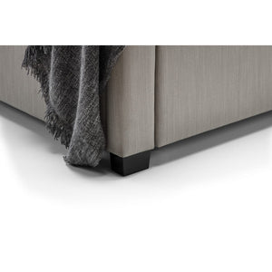 Gray upholstered bed with a textured blanket on a white background