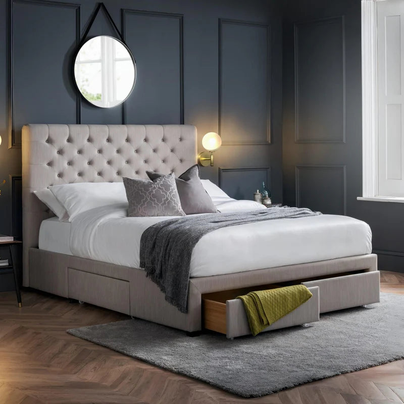 Gray upholstered bed with white bedding and a gray throw blanket on a white background