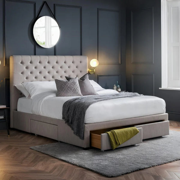 Gray upholstered bed with storage drawers in a bedroom setting.