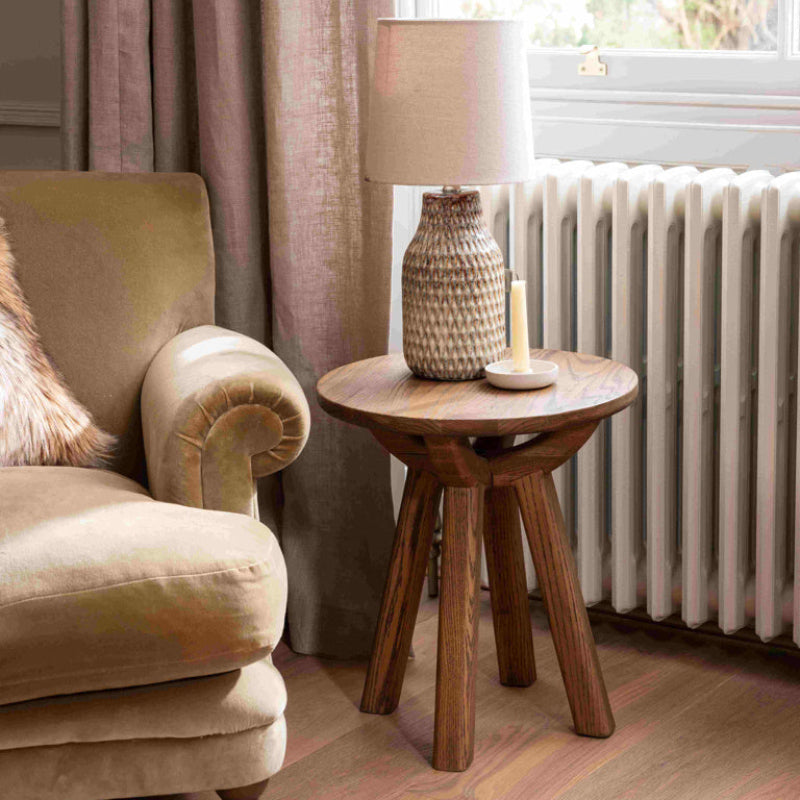 Wooden side table with a round top and four legs on a white background