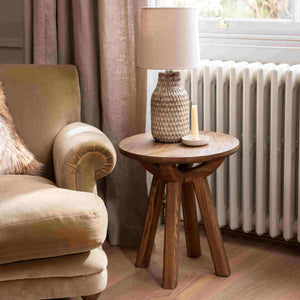Cozy living room with a beige armchair, wooden side table, and lamp.
