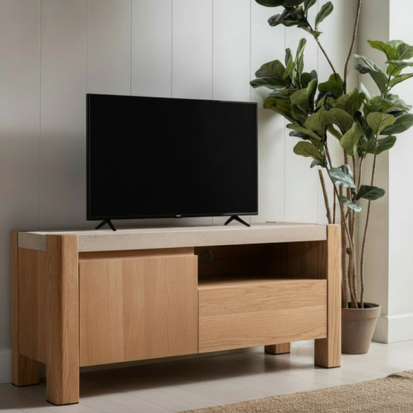 Wooden TV stand with a television on it, placed against a light-colored wall with plants in the background.